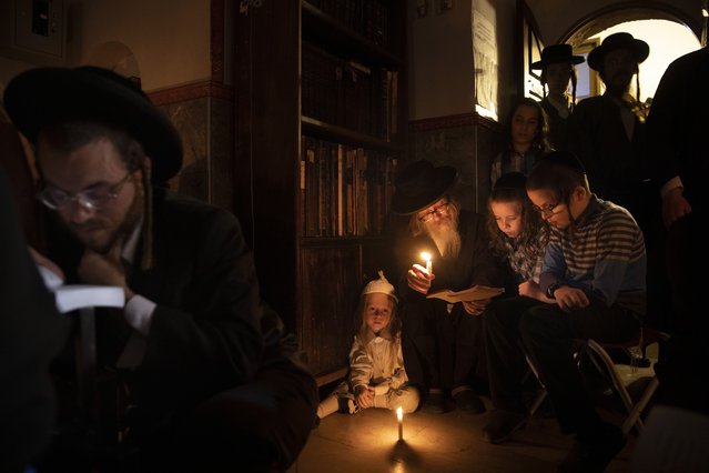 Ultra-Orthodox Jewish men and children read by candle light from the book of Eicha (Book of Lamentations) during the annual Tisha B'Av (Ninth of Av) fasting and a memorial day, commemorating the destruction of ancient Jerusalem temples, in the Ultra-Orthodox neighborhood of Mea Shearim in Jerusalem, Saturday, July 17, 2021. (Photo by Oded Balilty/AP Photo)
