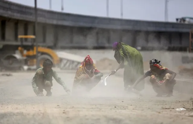 Labourers sweep dust and stones at a road construction site in Ahmedabad, India, May 3, 2016. (Photo by Amit Dave/Reuters)