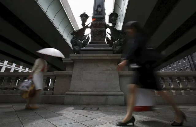 Pedestrians walk in front of a stone statue under a Metropolitan Expressway at a business district in Tokyo, Japan, May 25, 2015. (Photo by Yuya Shino/Reuters)