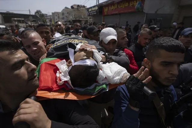 Palestinian mourners carry the body of Sanad Abu Atiyeh, 17 during his funeral in the West Bank refugee camp of Jenin, Jenin, Thursday, March 31, 2022. (Photo by Nasser Nasser/AP Photo)