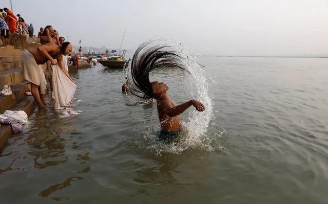 In this November 13, 2019, photo, a Hindu devotee takes a holy dip in the River Ganges in Varanasi, India. Varanasi is among the world's oldest cities, and millions of Hindu pilgrims gather annually here for ritual bathing and prayers in the Ganges River, considered holiest by Hindus. (Photo by Rajesh Kumar Singh/AP Photo/File)