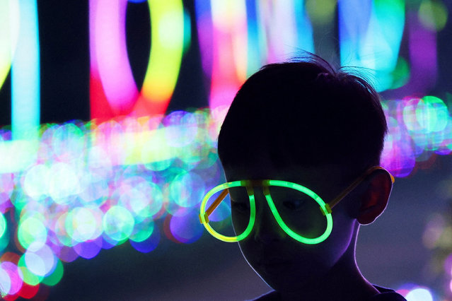 A boy wears glow stick glasses as he visits the Galactic Glow playground at Paris Van Java Resort Lifestyle Place in Bandung, West Java province, Indonesia on July 20, 2024. (Photo by Ajeng Dinar Ulfiana/Reuters)