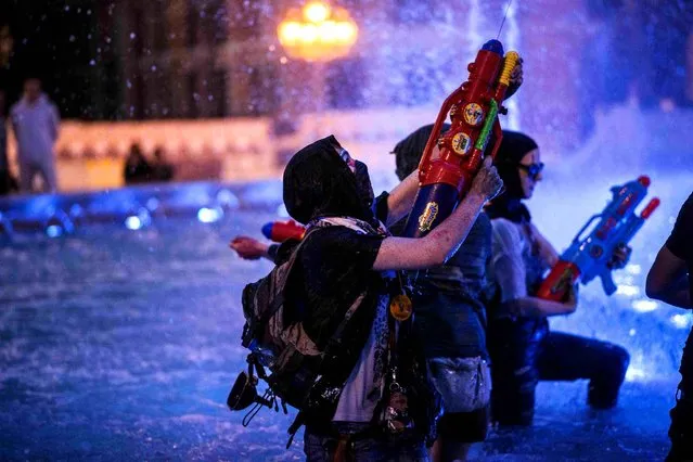 Protestors wearing masks use water guns to spray coloured paint on The Alexander the Great Fountain during an anti-government protest in Skopje on June 3, 2016, in a series of protests dubbed Colourful Revolution. Macedonia's president revoked on May 27 the pardons he had granted to 22 politicians implicated in a wiretapping scandal, after the move sparked outrage inside and outside the troubled Balkan country. (Photo by Robert Atanasovski/AFP Photo)