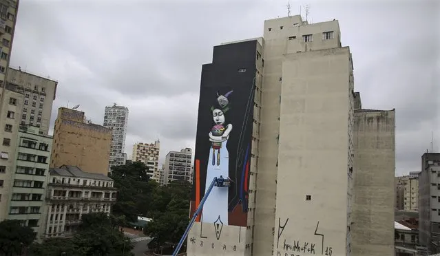 Tinho and Carlos Vergara (R), from Brazil, paint their work on a building during the International Festival of Street Art in Sao Paulo October 24, 2015. (Photo by Nacho Doce/Reuters)