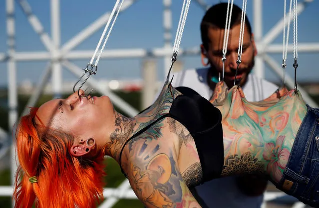 Professional body artist Dino Helvida (R), 27, inspects Kaitlin, 28, from the United States, as she is suspended from hooks pierced through her skin in Zagreb, Croatia June 7, 2016. (Photo by Antonio Bronic/Reuters)