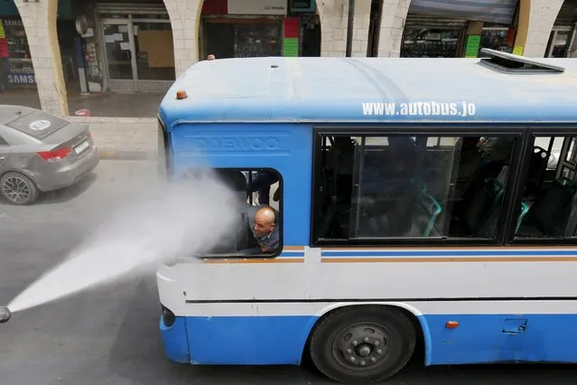 A bus driver reacts as Greater Amman Municipality personnel spray them with a water sprinkler in order to cool them down as part of measures to ease the effect of a heatwave, in Amman, Jordan, August 3, 2015. (Photo by Muhammad Hamed/Reuters)