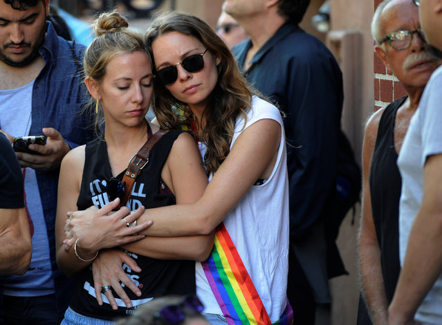 Two women hold each other at a vigil outside The Stonewall Inn on Christopher Street, considered by some as the center of New York State's gay rights movement, following the shooting massacre at Orlando's Pulse nightclub, in the Manhattan borough of New York, U.S., June 12, 2016. (Photo by Mark Kauzlarich/Reuters)