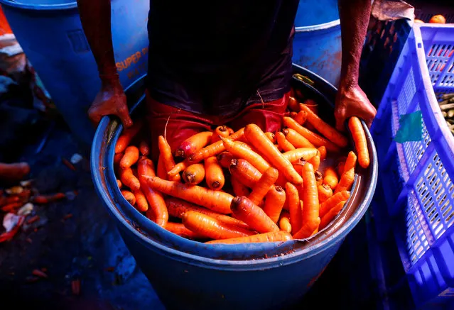 A worker washes carrots in a plastic drum at a wholesale vegetable market in Mumbai, India, June 14, 2016. (Photo by Danish Siddiqui/Reuters)