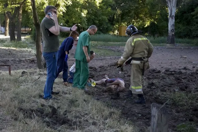 Paramedics and investigators check the body of a woman killed by shelling in the Kalininsky district of Donetsk, on the territory which is under the Government of the Donetsk People's Republic control, eastern Ukraine, Thursday, June 9, 2022. (Photo by Alexei Alexandrov/AP Photo)