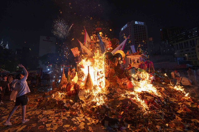 Malaysian Chinese perform prayers in front of the giant paper statue of the Chinese deity “Da Shi Ye” or “Guardian God of Ghosts” as it burns during the Chinese Hungry Ghost Festival in Kuala Lumpur, Monday, August 19, 2024. (Photo by Vincent Thian/AP Photo)