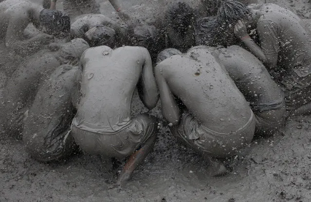 Festival goers wrestle in the mud during the annual Boryeong Mud Festival at Daecheon Beach on July 18, 2014 in Boryeong, South Korea. The mud, which is believed to have beneficial effects on the skin due to its mineral content, is sourced from mud flats near Boryeong and transported to the beach by truck. (Photo by Chung Sung-Jun/Getty Images)