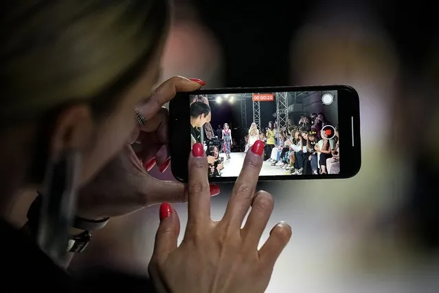 A spectator films on her smartphone as models display a collection by Russian designer Polina Mircheva during the Fashion Week at Zaryadye Park near Red Square in Moscow, Russia, Wednesday, June 22, 2022. (Photo by Alexander Zemlianichenko/AP Photo)