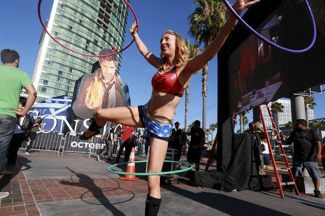 A staff member dressed as Wonderwoman, who gave her name as Hillary Hula, performs at the Gaslamp Quarter in Downtown San Diego during the 2014 Comic-Con International Convention in San Diego, California July 23, 2014. (Photo by Sandy Huffaker/Reuters)