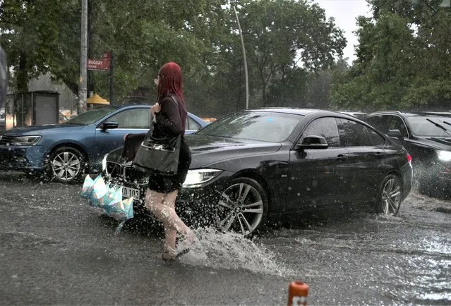 A woman walks in a flooded street in the city center of Ankara, Turkey, Saturday, June 11, 2022. Heavy rainfall in Turkey's capital on Saturday led to flooding that killed one person, authorities said. Ankara Mayor Mansur Yavas tweeted that 35 people had been rescued. He reported flooding in 300 locations, 35 fallen trees and the collapse of 23 roofs and three utility poles. (Photo by Burhan Ozbilici/AP Photo)