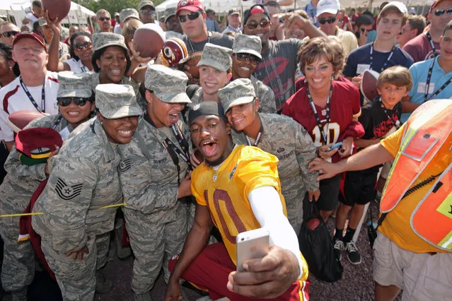 Washington Redskins NFL football team quarterback Robert Griffin III (10)  takes a photo with, from left foreground,  Lataya Stanley, Jamie Bowser. Angeline Mahoney and Brenda McFarland of the U.S. Air Force, after a joint practice with the New England Patriots in Richmond, Va., Wednesday, August 6, 2014. (Photo by Jay Paul/AP Photo)