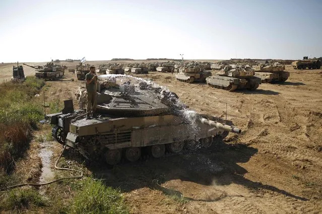 An Israeli soldier washes a tank at a staging area near the border with the Gaza Strip August 10, 2014. (Photo by Amir Cohen/Reuters)
