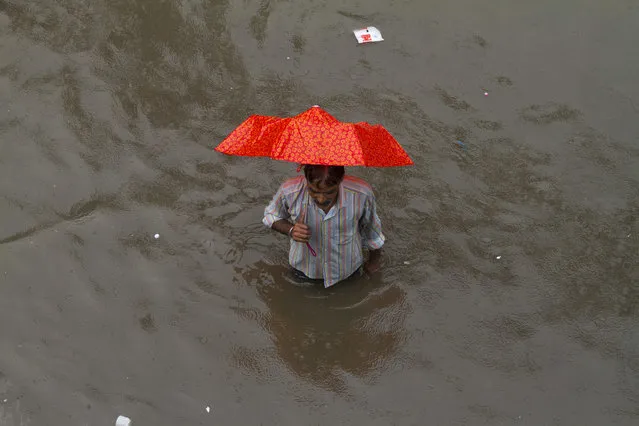 A pedestrian wades through a water logged street following heavy rains in Allahabad, India, Tuesday, July 25, 2017. The monsoon season in India runs from June to September. (Photo by Rajesh Kumar Singh/AP Photo)
