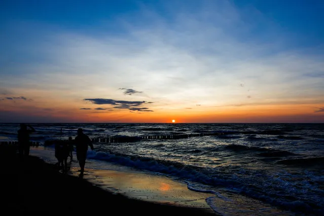 The sun sets over the Baltic sea as holidaymakers watch from the beach in Wroclaw, Poland on July 6, 2022. (Photo by Krzysztof Zatycki/Zuma Press Wire/Rex Features/Shutterstock)