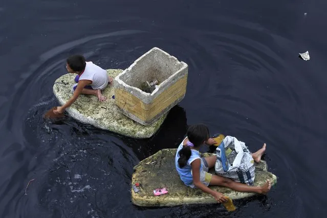 Children paddle, as they use discarded styrofoam as makeshift boats, to collect floating plastic recyclables on the Manila Bay to sell to junk shops for 10 pesos (2 cents) per kilogram, in Navotas City, north of Manila August 22, 2014. (Photo by Romeo Ranoco/Reuters)
