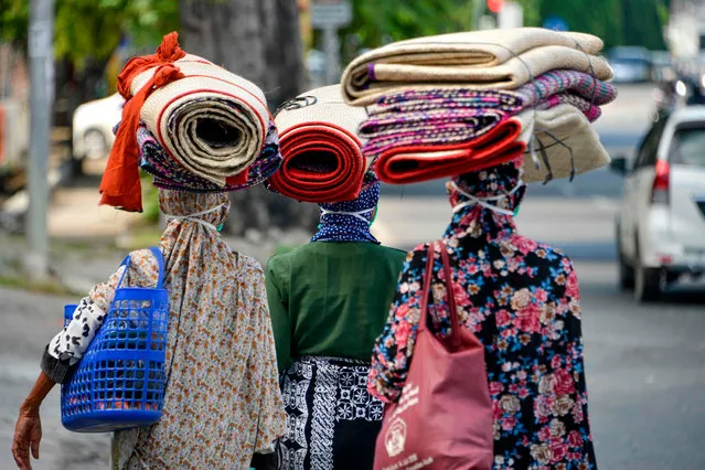 Women carry woven mats to sell as they walk on a street in Banda Aceh on April 15, 2020. (Photo by Chaideer Mahyuddin/AFP Photo)