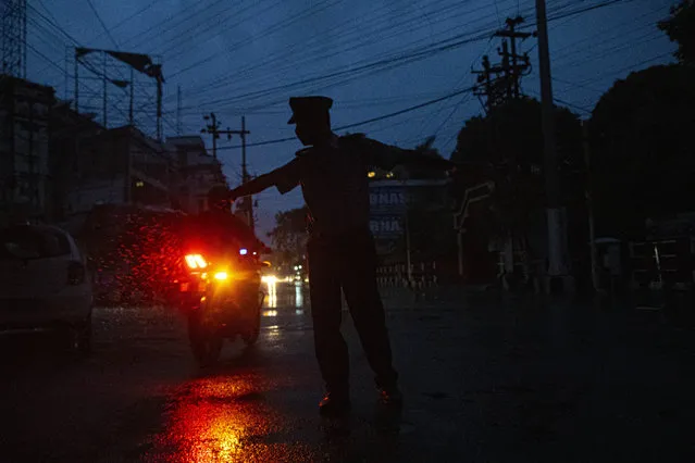An Indian traffic police man stops a motorist during nationwide lockdown in Gauhati, India, Tuesday, May 5, 2020. India's six-week coronavirus lockdown, which was supposed to end on Monday, has been extended for another two weeks, with a few relaxations. Locking down the country's 1.3 billion people has slowed down the spread of the virus, but has come at the enormous cost of upending lives and millions of lost jobs. (Photo by Anupam Nath/AP Photo)