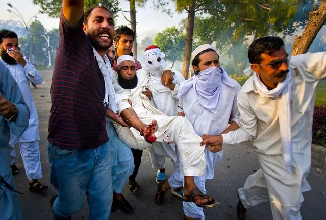 Protestors help their injured colleague during clashes with police as the tried to approach the U.S. embassy in Islamabad, Pakistan, on September 21, 2012. Four people were killed and dozens injured on a holiday declared by Pakistan's government so people could peacefully rally against the video. (Photo by Anjum Naveed/Associated Press)