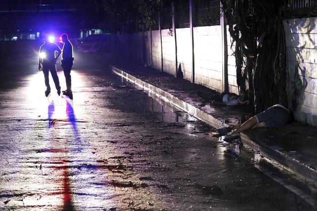 Filipino policemen stand next to dead bodies following a police operation against illegal drugs in Manila, Philippines, 10 August 2016. According to media reports, Philippine President Rodrigo Duterte has threatened to declare martial law if the country's judiciary interferes with his ongoing war against illegal drugs. Duterte made speech on 09 August before military troops in the southern island of Mindanao, making the remarks after Chief Justice Maria Lourdes Sereno wrote him a letter on behalf of the seven judges that were named in his list of alleged enablers of drug dealers. (Photo by Francis R. Malasig/EPA)