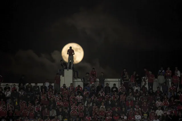 A full moon rises over supporters of the Wydad Athletic Club during the second leg of the CAF Champions League final soccer match against Egypt's Al Ahly Sporting Club, in Casablanca, Morocco, Saturday, November 4, 2017. Wydad defeated Al Ahly 2-1 on aggregate to win the CAF Champions League. (Photo by Mosa'ab Elshamy/AP Photo)