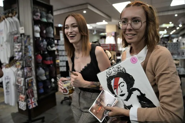 Customers purchase a T-shirt with a print of Queen Elizabeth II at a gift shop in London, Monday, September 12, 2022. Just days after the death of Queen Elizabeth II, unofficial souvenirs have rolled out at royal-themed gift shops in London and online marketplaces like Amazon and Etsy. (Photo by Kin Cheung/AP Photo)