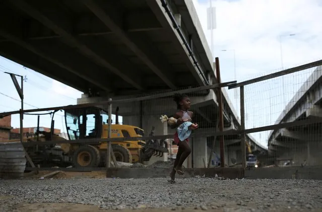 A child runs under a bridge of the Transolimpica BRT, an express road built through a shantytown to join the Rio 2016 Olympic venues of Deodoro and Barra da Tijuca, in the Vila Uniao favela of Rio de Janeiro, August 12, 2016. (Photo by Nacho Doce/Reuters)