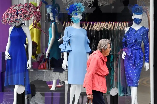 A woman walks past a window display of a couture shop called Nataliya in Ascot, Britain on June 16, 2020, as racing resumes behind closed doors after the outbreak of the coronavirus disease (COVID-19). (Photo by Toby Melville/Reuters)