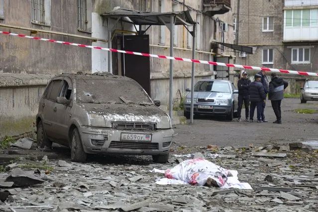 A covered lifeless body lies next to a damaged car after shelling by Ukrainian forces in Makiivka, Donetsk People's Republic, eastern Ukraine, Friday, November 4, 2022. (Photo by AP Photo/Stringer)