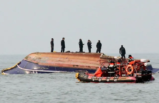 South Korean coastguard members search for missing persons after a fishing boat crashed with a fuel tanker at sea near the western port city of Incheon on December 3, 2017. Thirteen people were killed and two were missing after a fishing boat collided with a tanker off South Korea's west coast and capsized early on December 3, the country's coastguard said. (Photo by AFP Photo/Yonhap)