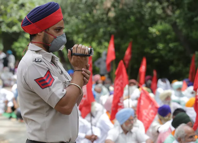 A police man records a video as activists of Communist Party of India (CPI) and their supporter parties' shout slogans during an anti-government protest in Amritsar, India, 08 July 2020. Protestors alleged that the center and the state governments have failed to tackle the COVID-19 issue. According to protesters, the Narendra Modi-led government has allowed the passing of laws which are against the interests of workers, farmers and common people. (Photo by Raminder Pal Singh/EPA/EFE)