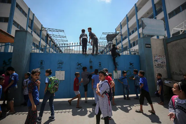 Palestinian refugee students standing on their school gate after the school was hit by an Israeli drone in Al-Shati refugee camp, western Gaza city, 13 August 2020. An educational institution run by United Nations Relief and Works Agency (UNRWA) was hit by an Israeli drone as Israeli warplanes were targeting several locations of Hamas in Gaza city, according to reports. (Photo by Mohammed Saber/EPA/EFE)