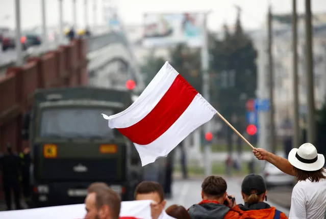 A participant waves a historical white-red-white flag of Belarus during an opposition demonstration to protest against presidential election results at the Independence Square in Minsk, Belarus on August 23, 2020. (Photo by Vasily Fedosenko/Reuters)