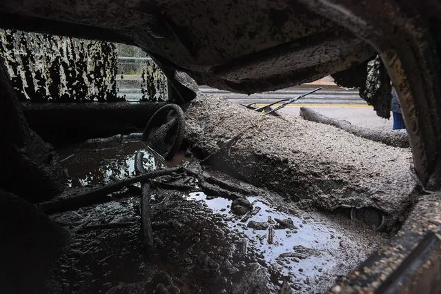 Mud fills the interior of a car destroyed in a rain- driven mudslide in a neighborhood under mandatory evacuation in Burbank, California, January 9, 2018. Mudslides unleashed by a ferocious storm demolished homes in southern California, authorities said Tuesday. Five people were reported killed. (Photo by Robyn Beck/AFP Photo)