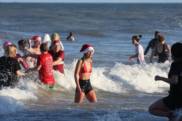 Participants in fancy dress costumes take to the freezing sea on December 26, 2022 in Cromer, United Kingdom. The North Norfolk Beach Runners are holding the Boxing Day Dip for the first time for three years after the annual event was cancelled for two years due to Covid. Money raised from the gathering this year is going to be donated to Sarcoma UK. (Photo by Martin Pope/Getty Images)