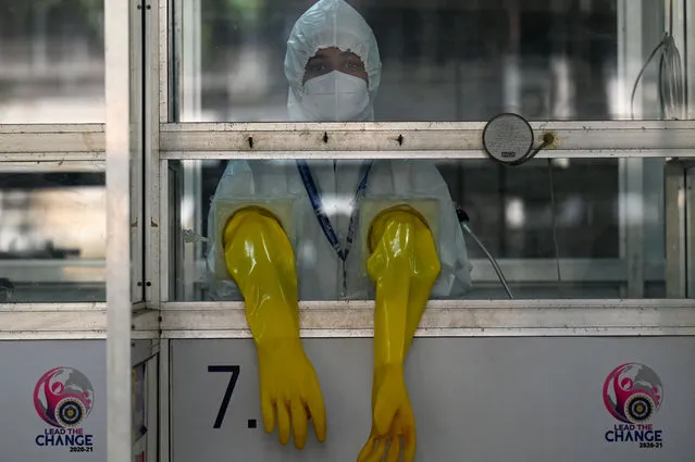 A health worker wearing personal protective equipment (PPE) stands inside a swab collection booth to check preparation of Covid-19 test facilities at a hospital in Mumbai on December 27, 2022. (Photo by Punit Paranjpe/AFP Photo)