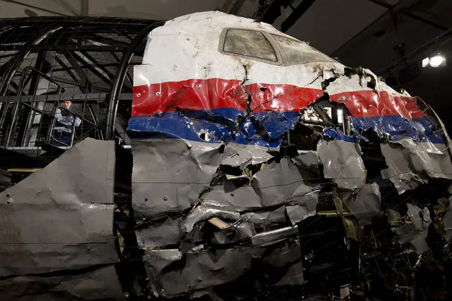 A Dutch Military Policeman, left inside, guards part of the reconstructed cockpit, right, and forward section of the fuselage after the Dutch Safety Board presented it's final report into what caused Malaysia Airlines Flight 17 to break up high over Eastern Ukraine last year, killing all 298 people on board, during a press conference in Gilze-Rijen, central Netherlands, Tuesday, October 13, 2015. (Photo by Peter Dejong/AP Photo)