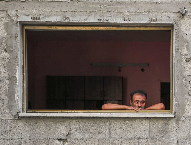 A man looks out of a window as Palestinians inspect the site and search for casualties of an overnight Israeli air strike on a house at al-Shati (Beach) refugee camp, in Gaza City, on July 15, 2025. (Photo by Mahmoud Issa/Reuters)