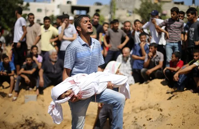 A Palestinian man reacts as he carries the body of a girl from the Abu Nejim family, whom medics said was killed along with other eight family members by an Israeli air strike, before her burial at a cemetery in Beit Lahiya in the northern Gaza Strip, in this August 4, 2014 file photo. (Photo by Mohammed Salem/Reuters)