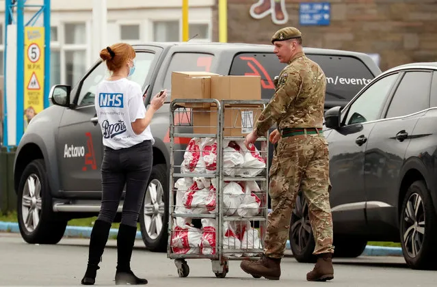 A soldier speaks to a woman wearing an NHS shirt at the Pontins Southport Holiday Park while preparing to support Liverpool ahead of a mass testing for the coronavirus disease (COVID-19), in Ainsdale, Britain, November 5, 2020. (Photo by Phil Noble/Reuters)