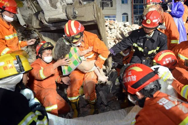 This picture taken on October 10, 2016 shows rescuers carrying a young girl who was rescued at an accident site after four buildings caved in during the early hours in Wenzhou, eastern China's Zhejiang province. (Photo by AFP Photo/Stringer)
