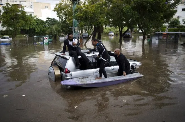 Israelis on a small motor boat help a motorist (L) after his vehicle got stuck on a flooded street in the southern city of Ashkelon, Israel, November 9, 2015. (Photo by Amir Cohen/Reuters)