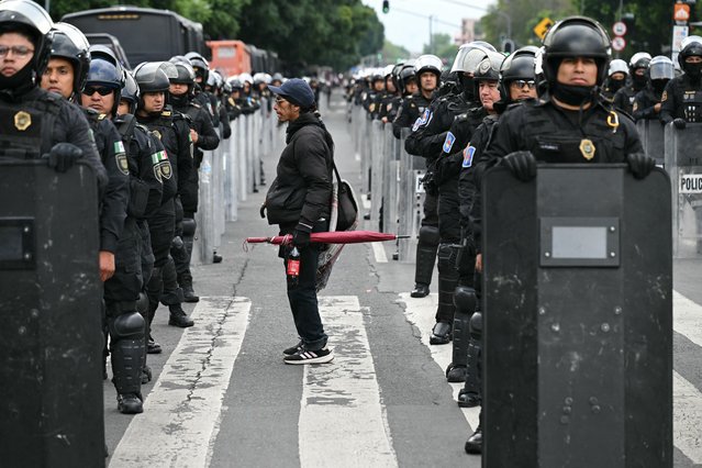 A demonstrator stands amid rows of riot police officers during a rally commemorating the 57th anniversary of the 1968 Tlatelolco student massacre in Mexico City on October 2, 2025. (Photo by Yuri Cortez/AFP Photo)