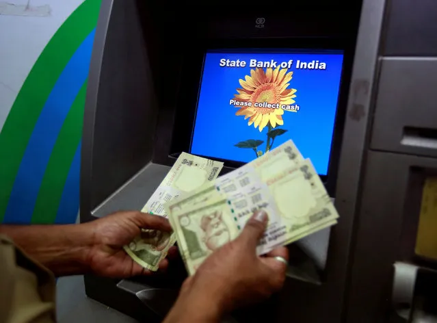 A man counts money after withdrawing it from a State Bank of India automated teller machine (ATM) in Mumbai, India, March 9, 2016. (Photo by Danish Siddiqui/Reuters)