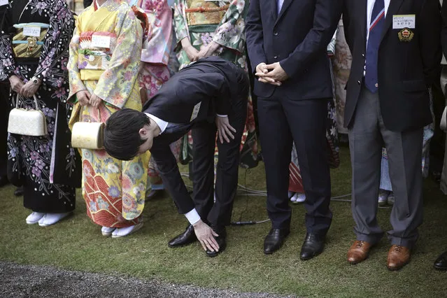 Pyeongchang Olympics figure skating gold medalist Yuzuru Hanyu, center, cleans his shoe during the Imperial spring garden party at the Akasaka Palace imperial garden in Tokyo Wednesday, April 25, 2018. (Photo by Eugene Hoshiko/AP Photo)