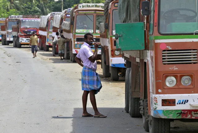 A truck driver brushes his teeth next to his parked truck while waiting to get his loads cleared to cross a checkpoint at the Commercial Taxes Department check post at Walayar in Palakkad district in southern Indian state of Kerala, India September 5, 2015. (Photo by Sivaram V/Reuters)