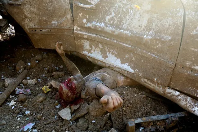 An injured man is pictured under a vehicle following an explosion in Beirut's port area, Lebanon on August 4, 2020. When Reuters photographer Mohamed Azakir saw a man pinned under a vehicle, covered in a thick film of rubble and blood, he thought the man was dead. But then the man opened his eyes and began waving his arms and asking for help. Azakir called over some rescuers who were nearby. In a series of photographs, he recorded the rescue of the man, while also helping the rescuers move the car to free him. (Photo by Mohamed Azakir/Reuters)